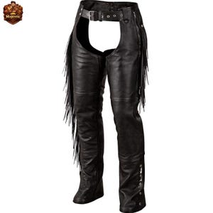 Puede incluir: Chaps de cuero negro con flecos en los laterales. Los chaps tienen un cinturón con cierre de hebilla en la cintura y remaches decorativos. Diseñados para llevar sobre pantalones, ofrecen protección y estilo.