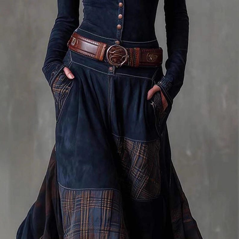 May include: A dark blue outfit featuring a long-sleeved top with button details and a matching skirt. The outfit is cinched at the waist with a brown leather belt with a large, decorative buckle. The skirt has plaid patches.