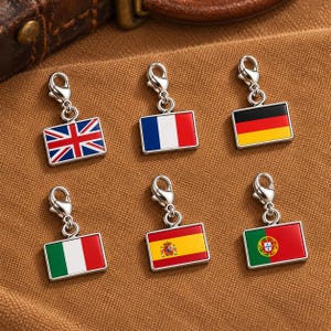 May include: Six rectangular metal charms featuring the national flags of the United Kingdom, France, Germany, Italy, Spain, and Portugal. Each charm is equipped with a silver-toned lobster clasp for attachment to jewelry or accessories.