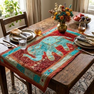 May include: A rectangular table runner featuring a prominent turquoise elephant appliqué centered on a deep red fabric background. The runner is decorated with intricate gold embroidery, small mirrors, and patchwork borders in shades of blue and red.