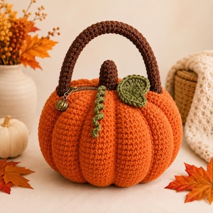 May include: A round, orange crocheted pumpkin-shaped handbag with a dark brown crocheted handle and a small brown stem. It features a green crocheted leaf, a green curly vine, and a metal zipper closure with a small pumpkin-shaped charm.