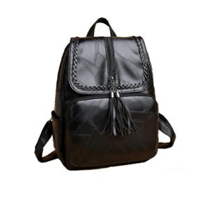 K&ouml;nnte beinhalten: Schwarzer Rucksack mit geflochtenem &Uuml;berschlag und Quasten-Rei&szlig;verschlussanh&auml;nger. Der Rucksack hat eine Vordertasche und verstellbare Schultergurte. Das Material ist strukturiert.