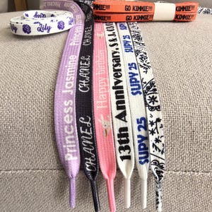 Puede incluir: Cordones de zapatos variados en varios colores, incluyendo morado, negro, rosa, blanco y naranja. Los cordones presentan textos impresos como "Princess Jasmine", "CHANEL", "Happy birthday" y "13th Anniversary". Algunos cordones tienen patrones decorativos.