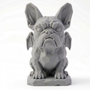 Peut inclure: Une sculpture géométrique gris clair en low-poly représentant un bouledogue français avec des ailes de chauve-souris, posée sur une base rectangulaire. Le texte FDM-3DG-1A est gravé sur le devant. La figurine présente une surface facettée.