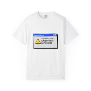 May include: White t-shirt with a blue and grey graphic resembling a computer error message. The message reads "System Error: Emotionally Exhausted" with a yellow warning triangle. The shirt has a crew neck and short sleeves.