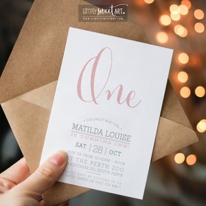 Puede incluir: Una tarjeta de invitación rosa y blanca con el texto "One" en una fuente de letra cursiva rosa. La tarjeta es para una fiesta de cumpleaños para Matilda Louise, que cumple un año. La fiesta se celebrará el sábado 28 de octubre en el zoológico de Perth.
