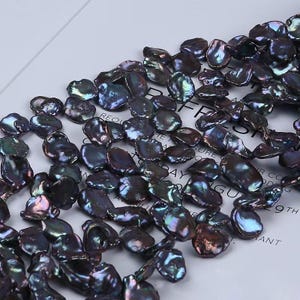 Può includere: Primo piano di una collezione di perle barocche scure e iridescenti. Le perle hanno una forma irregolare e una superficie lucida, che riflette sfumature di viola, verde e blu. Queste perle naturali sono ideali per la creazione di gioielli.