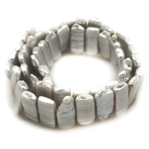 May include: A strand of light grey, rectangular freshwater pearls. The pearls have a lustrous, pearlescent sheen and are strung together to form a circular shape. The pearls are smooth and have a slightly irregular shape.