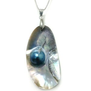 May include: A pendant necklace with an iridescent, oval shell and a dark blue pearl. The shell is suspended from a silver chain. The pendant has a silver-coloured bail. A unique piece of jewellery.