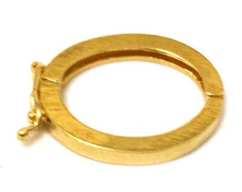 Könnte beinhalten: Ein goldfarbener, kreisförmiger Schmuckverschluss mit einer Scharnieröffnung. Der Verschluss besteht aus einem glänzenden, metallischen Material und hat ein einfaches, funktionales Design. Der Verschluss dient zur Sicherung von Schmuckstücken.