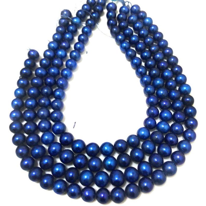 Puede incluir: Varias hebras de cuentas azul oscuro, probablemente para joyer&iacute;a. Las cuentas son redondas y tienen un acabado brillante. La disposici&oacute;n muestra m&uacute;ltiples hebras, posiblemente para collares o pulseras.