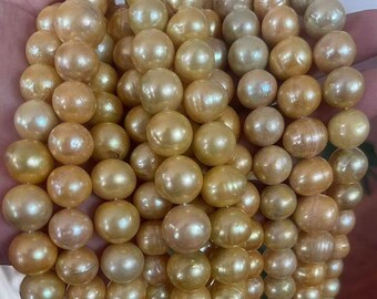 Könnte beinhalten: Nahaufnahme einer Sammlung goldfarbener Perlen. Die Perlen sind rund und haben einen glänzenden Glanz, mit Farbvariationen von hellgold bis zu einem tieferen Ton. Sie scheinen aufgefädelt zu sein, was auf eine Halskette oder ein ähnliches Schmuckstück hindeutet.