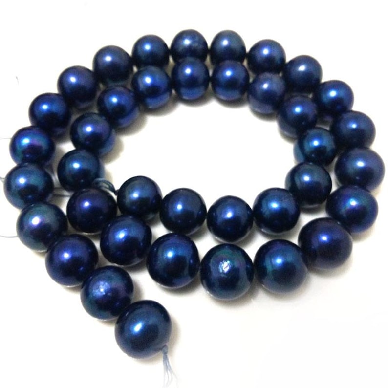 Puede incluir: Un hilo de cuentas redondas de color azul marino oscuro con un acabado liso y brillante. Las cuentas est&aacute;n dispuestas en un patr&oacute;n circular y ensartadas en un hilo fino de color claro, mostrando un tama&ntilde;o uniforme y color azul.