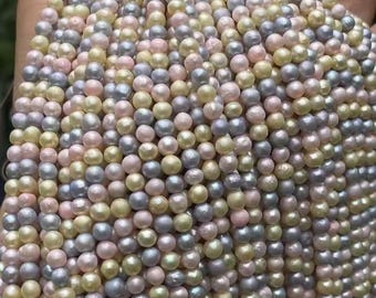 Könnte beinhalten: Eine Ansammlung runder, glänzender Perlen in einer sanften Pastellpalette aus blassem Rosa, cremigem Gelb und hellem Lavendelgrau. Die Perlen sind in mehreren vertikalen Strängen angeordnet und zeigen ihre glatten, schimmernden Oberflächen.