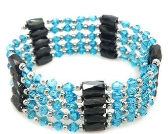 Könnte beinhalten: Ein mehrreihiges Wickelarmband mit der Aufschrift No. 44, bestehend aus Reihen von leuchtend blauen facettierten Kristallperlen, kleinen silberfarbenen Metallzwischenperlen und größeren, rechteckigen, polierten schwarzen Hämatitperlen.