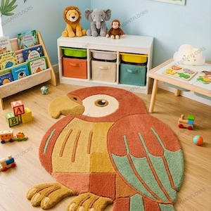 May include: A colorful parrot-shaped rug with a patchwork design in shades of orange, yellow, and green. The rug is placed on a wooden floor in a child's room, with toys and decorative elements visible.