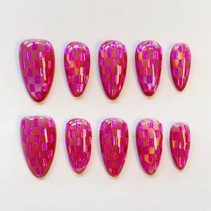 Op de afbeelding: Een set van tien kunstnagels in amandelvorm met een glanzende afwerking. Elke nagel heeft een levendig dambordpatroon bestaande uit afwisselende vierkantjes in diep magenta en reflecterend, metallic felroze foliemateriaal.