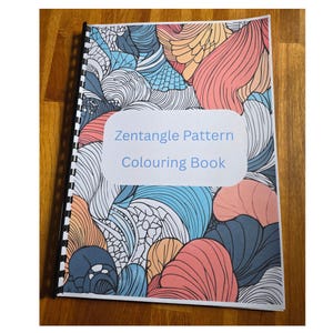May include: A spiral-bound colouring book with a cover displaying a Zentangle pattern. The design features abstract shapes in blue, coral, orange, and white. The title "Zentangle Pattern Colouring Book" is on a white oval.