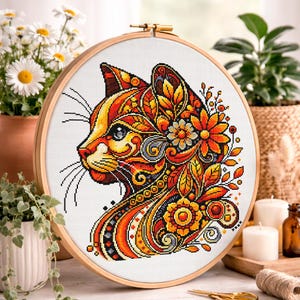 May include: A cross-stitch cat profile with floral and leaf patterns in orange, yellow, and red hues, displayed in a wooden embroidery hoop. The craft project showcases detailed stitching and vibrant colours, perfect for home decor.