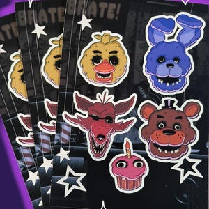 May include: A stack of black cards featuring colorful cartoon character stickers. The stickers include a yellow duck, a blue rabbit, a red fox, and a brown bear. White stars and the word "ATE" are also visible.