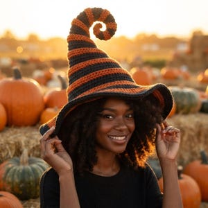 May include: A crocheted hat featuring a tall, spiraled point and a wide brim, designed with alternating horizontal stripes in black and orange yarn. The hat has a textured, ribbed appearance throughout the entire structure.