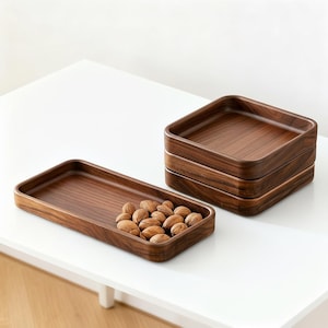 Può includere: Una tazza di ceramica bianca con manico nero e la scritta "But First, Coffee" in nero, in grassetto. La tazza è appoggiata su una superficie di legno. La tazza è alta circa 10 cm.