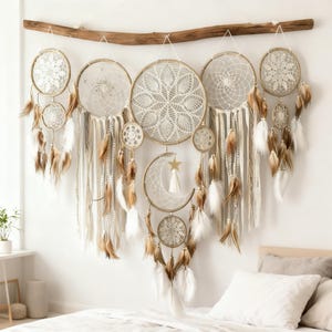 以下が含まれることがあります： 手作りの大きなドリームキャッチャーの壁掛け。さまざまなサイズの複数の円形の織りフレームがあり、複雑なレース模様、羽、リボンで飾られています。三日月と星のアクセントが天体の雰囲気を添えています。天然の木の枝から吊り下げられています。