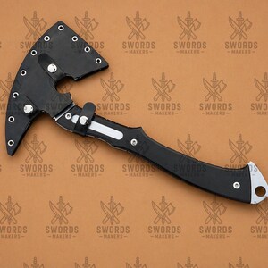 May include: A black axe with a curved blade and handle. The axe head is made of black metal and has a curved blade. The handle is also black and has a silver accent. The text "SWORDS -MAKERS-" is repeated across the background.