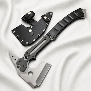 May include: A tactical axe with a black handle and a silver blade, accompanied by a black leather sheath. The axe features a unique design with a sharp edge and a pointed end. The sheath has a belt loop for easy carrying.