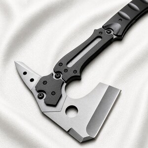 May include: A tactical axe with a black handle and a silver blade. The axe head features a sharp blade, a pointed end, and a circular hole. The handle has a textured grip for secure handling. The axe is designed for outdoor and survival use.