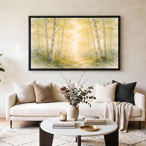 May include: A living room scene featuring a framed landscape painting of a forest with birch trees. A white sofa with throw pillows and a blanket is in front of a marble coffee table with decor. A potted plant and side table complete the room.