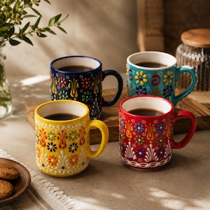 Peut inclure: Quatre tasses à café en céramique remplies de café, chacune avec une couleur et un motif floral différents. Les tasses sont jaunes, bleues, turquoise et rouges. Les tasses sont sur une planche de bois.