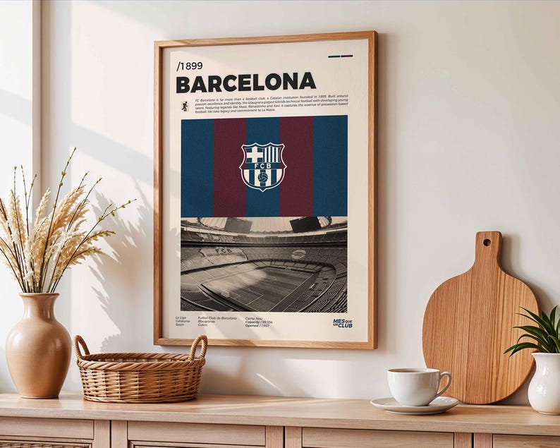 May include: A framed poster featuring the FC Barcelona crest and stadium. The poster has a cream-colored background with the text "BARCELONA" and other details. The crest is centered above a blue and maroon striped design.