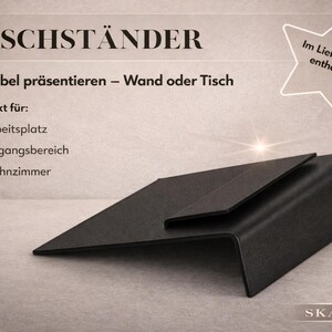 May include: A black, angled display stand with a modern design. The stand is made of a matte material and features the text "TISCHST&Auml;NDER" and "SKARLINE". The image also includes text in German about its flexibility for wall or table use.