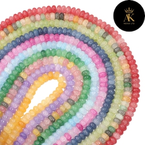 Puede incluir: Una colección de cuentas de piedras preciosas coloridas en un arcoíris de tonos, desde el rojo hasta el amarillo. Las pequeñas cuentas redondas están ensartadas, creando un efecto multicolor. La imagen está bien iluminada, mostrando la variedad de colores.