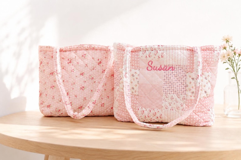Pu&ograve; includere: Due borse tote trapuntate rosa, con motivi floreali e patchwork. Una borsa ha il nome "Susan" ricamato. Le borse hanno manici coordinati e sono esposte su un tavolo di legno.