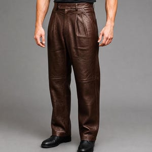 Puede incluir: Pantalones de cuero marrón oscuro con diseño de cintura alta, pliegues frontales, cierre de botón y costuras horizontales en las rodillas. Estos pantalones de corte recto tienen un acabado liso y pulido, combinados con zapatos negros.
