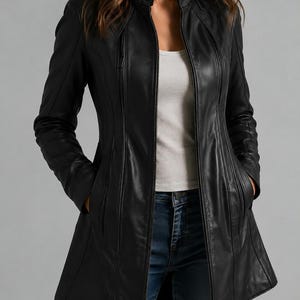 May include: A black leather jacket featuring a stand-up collar with a snap button closure, a full-length front zipper, and vertical zippered pockets. The jacket has long sleeves and a tailored fit that extends to the upper thigh area.