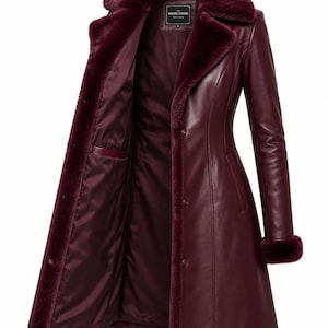 May include: A burgundy leather coat featuring a plush faux fur collar and matching fur cuffs. The coat has a button-front closure, a smooth satin-like interior lining, and a label at the neck that reads Genuine Leather.