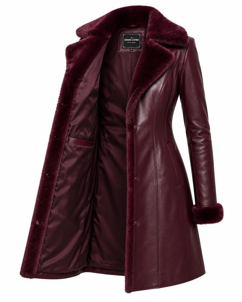 May include: A burgundy leather coat featuring a plush faux fur collar and matching fur cuffs. The coat has a button-front closure, a smooth satin-like interior lining, and a label at the neck that reads Genuine Leather.