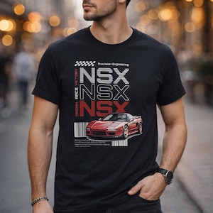 Könnte beinhalten: Schwarzes T-Shirt mit einer roten Sportwagen-Grafik und dem Text "NSX" in Weiß und Rot. Das Shirt enthält auch die Wörter "Precision Engineering" und "Dream Race Victory".