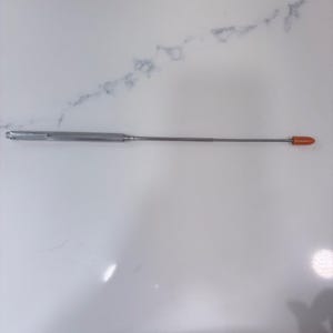 May include: A silver-colored telescopic pointer with a metallic body and a pocket clip on one end. The extendable rod features a smooth, thin design that terminates in a small, rounded, bright orange tip at the far end of the tool.