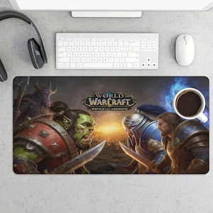 May include: A rectangular World of Warcraft mousepad featuring a battle scene with an orc and a human warrior. The mousepad has the game's logo and the words "Battle for Azeroth". A cup of coffee, keyboard, mouse, and headphones are also visible.