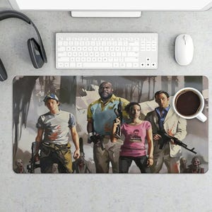 Könnte beinhalten: Rechteckiges Mauspad mit einer Gruppe von vier Charakteren aus dem Videospiel Left 4 Dead, die Waffen halten. Die Charaktere sind vor dem Hintergrund eines Waldes und Zombies platziert. Eine Tasse Kaffee und Computerzubehör sind ebenfalls sichtbar.