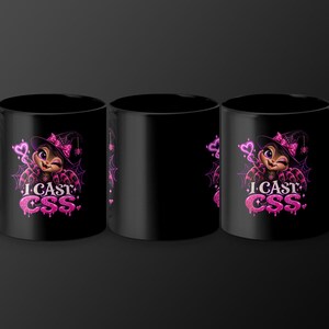 May include: A black ceramic mug featuring a graphic of a cartoon spider wearing a witch hat and a pink bow. The design includes a glowing pink heart, spiderwebs, and the text "I CAST CSS" in a dripping, glittery pink font style.