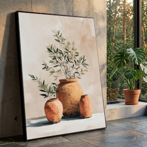 Puede incluir: Una impresión artística enmarcada que presenta una composición de naturaleza muerta. La obra de arte representa tres jarrones de color terracota, con un jarrón central grande que contiene ramas verdes y frondosas. El fondo es beige neutro, y la impresión está colocada contra una pared de hormigón.