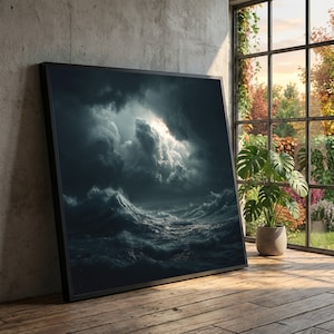 Peut inclure: Une impression encadrée représente une mer agitée sous un ciel orageux. Des vagues sombres et déchaînées s'écrasent sous des nuages menaçants, avec un aperçu de la lumière du soleil. L'œuvre est exposée sur un sol en bois, près d'une fenêtre.