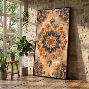 May include: A framed wall art print featuring a detailed mandala design in shades of orange, brown, and navy blue. The artwork has a vintage, textured appearance and is displayed against a neutral background. The print is leaning against a brick wall.
