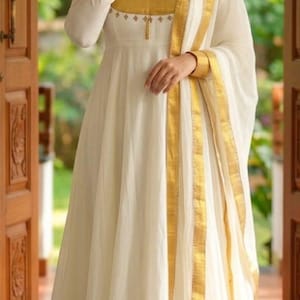 May include: A floor-length off-white dress featuring long sleeves with gold cuffs, a gold bodice panel with small embroidered details, and a wide gold border at the hem. A matching off-white dupatta with a gold border is draped over one shoulder.