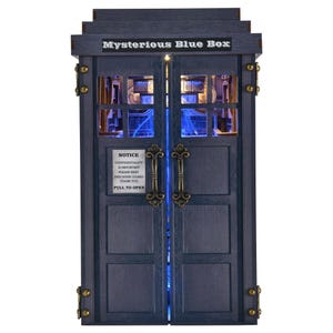 May include: A blue wooden box with the text "Mysterious Blue Box" on top. The box has two doors with ornate handles and a sign that reads "Notice Confidentiality is Important Please Keep This Door Closed Thank You Pull to Open."